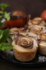 Freshly baked apple roses and mint on table, closeup