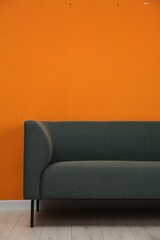 One stylish sofa near orange wall indoors