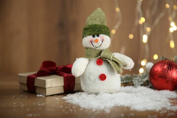 Cute decorative snowman and other Christmas decor on wooden table