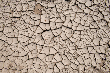 Overhead view of dry, cracked soil. Drought conditions have caused water to recede on a riverbed, creating arid conditions in the soil. 