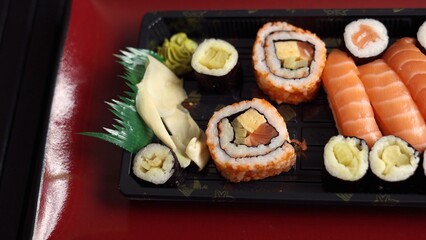 Traditional sushi on red plate with dipping sauce captures essence of Japanese cuisine. Elegant dining experience highlights authentic flavors, combining fresh sushi with classic sauces. 