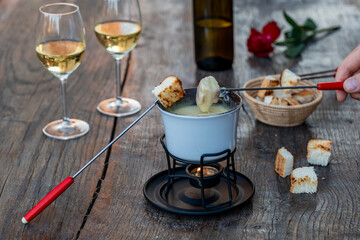 Fondue with tasty melted cheese, forks, breads and wine on wooden table, closeup