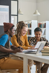 Vertical portrait of multiethnic young people using tablet while studying online in school or...