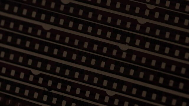 Pellicole da 35mm disposte verticalmente in un album cartaceo con una luce che le illumina passando da sinistra a destra e viceversa.