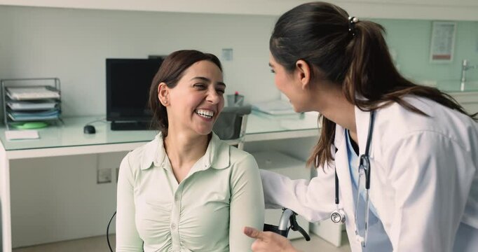 Young Indian doctor encouraging 35s woman with disability. Smiling optimistic female patient sit in wheelchair listening nurse gives hope and psychological support at visit in hospital. Rehabilitation