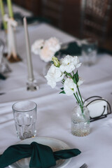 Empty tableware set, candles, tablecloth, flowers, decorated table with glass crystal stand in restaurant indoor. Photography, design concept for banquet.