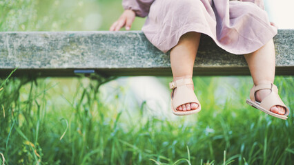 Toddler relaxing on a bench with the grass in background
