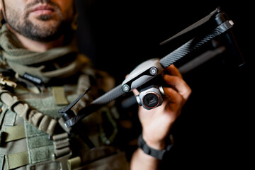 A male military drone operator holds a quadcopter with a camera in his hand. © Dmitri