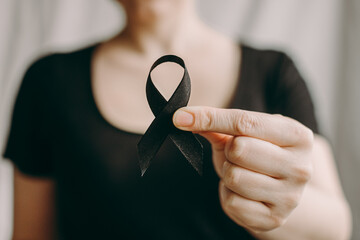 The woman 's hand holds black Ribbon for symbol Melanoma and skin cancer. Narcolepsy, Primary Biliary Cirrhosis, Sleep Apnea Disorders
