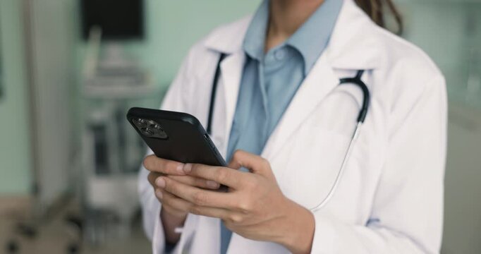 Close up of female medical worker using cellphone at workplace, provide instant access to medical reference apps, databases, clinical guidelines, look up information, or consulting patients remotely