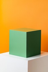 A large green cube sits on a white pedestal, creating a striking contrast against a bright orange background, ideal for showcasing products or artwork