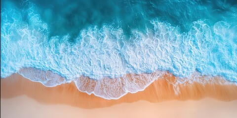 Fototapeta premium Aerial view of ocean waves crashing on a sandy beach creating a stunning blend of blue, white, and beige.
