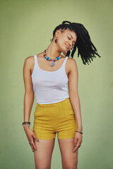 Fashion, dreadlocks and woman in studio with casual, cool and trendy outfit for confidence. Calm, smile and female person with traditional jewelry for accessory with clothes by green background.