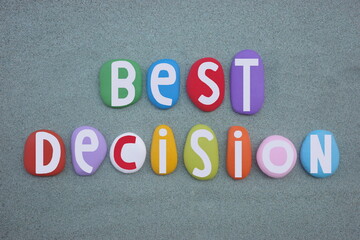 Best decision, creative slogan composed with multi colored stone letters over green sand