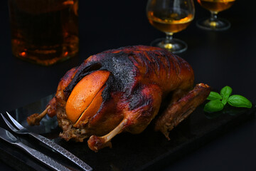 baked duck with oranges and whiskey in the background, still life in dark colors