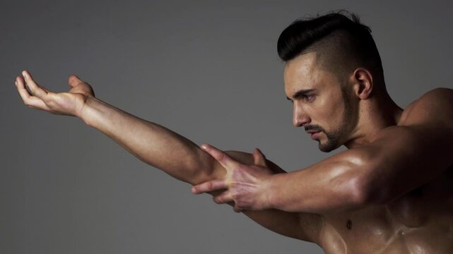 Muscular sexy man man flexing biceps. Male athlete, sportsman flexing bicep, looking at muscle biceps. Male Muscular biceps arm. Hand, man arm biceps Close-up. Strong, sexy and topless male model.