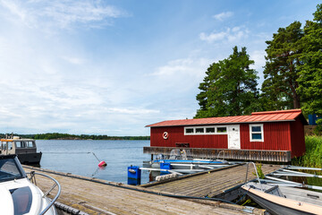 Fototapeta premium traditional red wooden fisherman's house with white door and windows on the Swedish archipelago at the water's edge