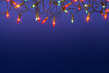 Christmas lights string on blue background with copy space