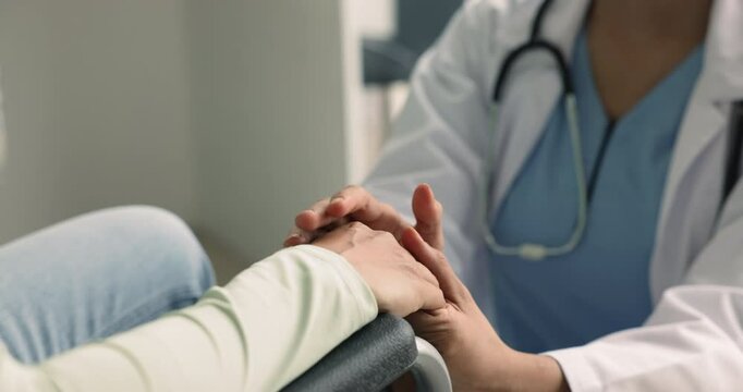 Close up view unknown woman doctor comforting patient with movement impairment, female sitting in wheelchair listening supporting words of friendly kind therapist. Rehabilitation, empathy, health-care
