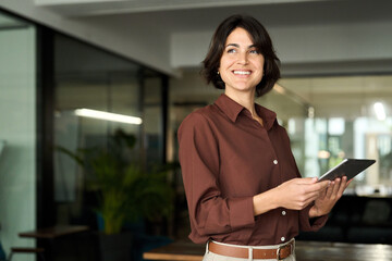 Happy young Hispanic professional business woman using tab standing in office. Happy businesswoman...