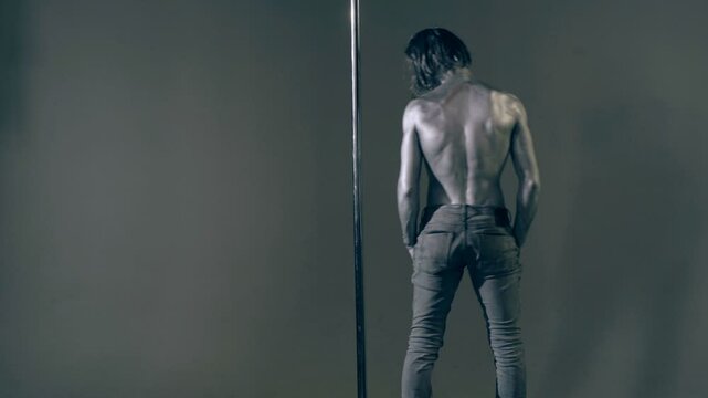 Strip dancer. Fit slim muscular man on pole dance. Pole dancer on pylon. Shirtless strong sexy man dancing. Male flexibility, and grace. Guy performing trick on pole. Male athlete doing acrobatic