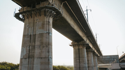 Dramatic underpass view of towering concrete bridges against the sky, capturing modern...