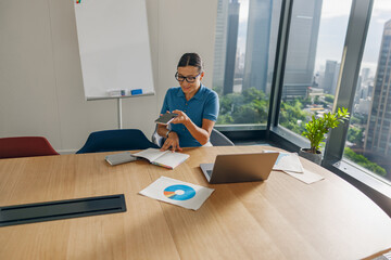 A highly focused professional fully engages with her smartphone while working in a sleek, modern office environment