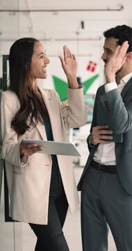 Multiethnic teammates met in office, look at digital tablet screen, engaged in discussion, share ideas, reached positive outcome, give high five, celebrate joint success. Sales, good profit, business
