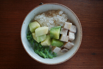 A close-up view of a refreshing traditional Thai dessert featuring a mix of diced taro, green...