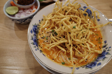 A flavorful bowl of Khao Soi, a traditional Northern Thai noodle dish, served in a beautiful...