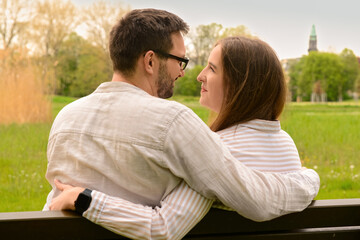 Fototapeta premium Beautiful loving couple sitting on bench and hugging in park