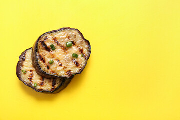 Delicious grilled eggplants on yellow background