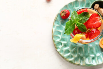 Glass of infused water with strawberry and lemon on light background