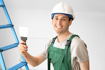 Male worker with putty knife in room