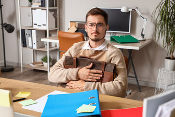 Stressed young man with briefcase working under deadline in office