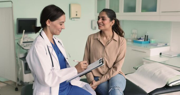Female nurse filling patient card while ask questions about symptoms at her regular health check-up visit in private clinic, to get professional medicare. Healthcare, medical insurance and services
