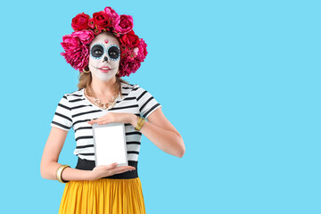 Young woman with tablet computer on blue background. Mexico's Day of the Dead (El Dia de Muertos)...
