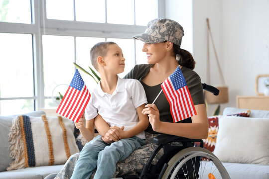 Female soldier and her little son with USA flags in wheelchair at home
