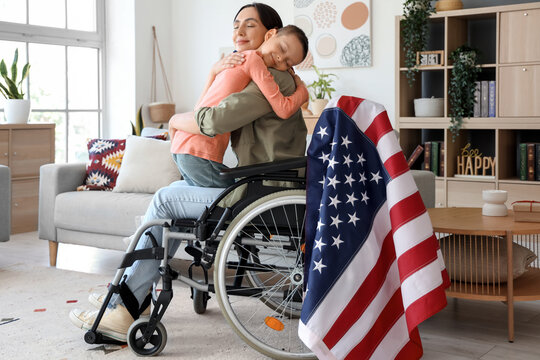 Little boy hugging his mother in wheelchair at home. Veterans Day celebration