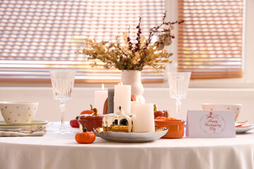 Festive table setting with burning candles, pumpkins and greeting cards for Thanksgiving Day