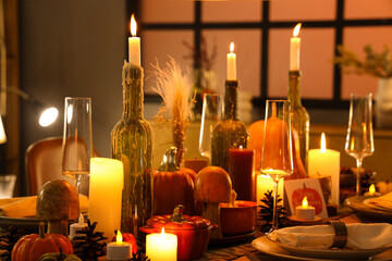 Festive table setting with burning candles, pumpkins and greeting cards for Thanksgiving Day at evening