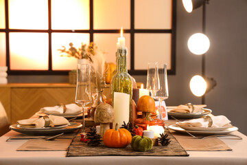 Beautiful table setting with burning candles, pumpkins and greeting cards for Thanksgiving dinner...