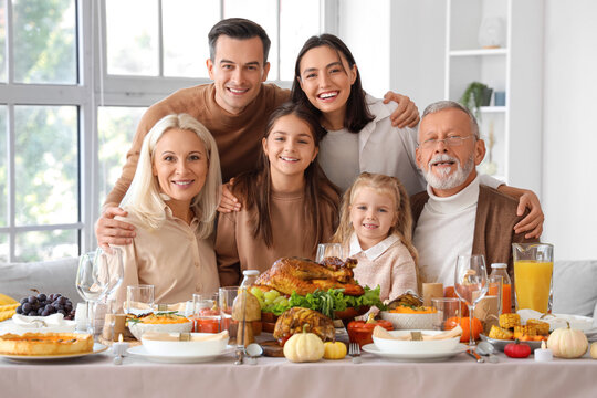 Happy family having dinner at festive table on Thanksgiving Day