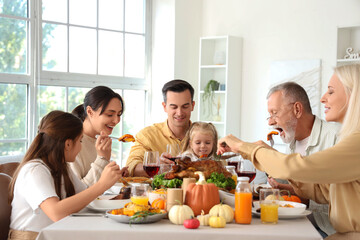Happy family having dinner at festive table on Thanksgiving Day
