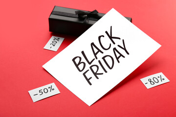 Greeting card with text BLACK FRIDAY, gift box and discount tags on red background