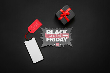 Greeting card with text BLACK FRIDAY SALE, gift box and mobile phone on dark background