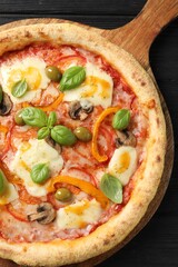 Delicious vegetarian pizza on black wooden table, top view