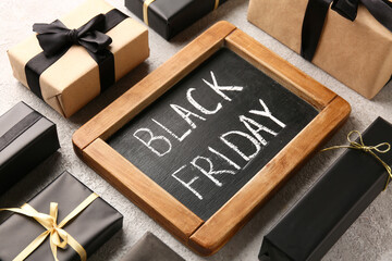 Chalkboard with text BLACK FRIDAY and gift boxes on white grunge table