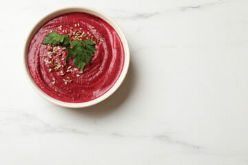 Tasty beetroot hummus, seeds and parsley in bowl on white marble table, top view. Space for text