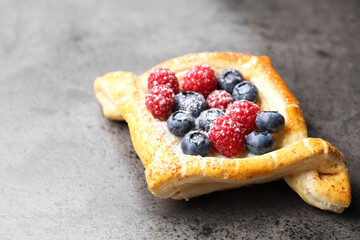 Tasty puff pastry with berries on grey table, closeup. Space for text